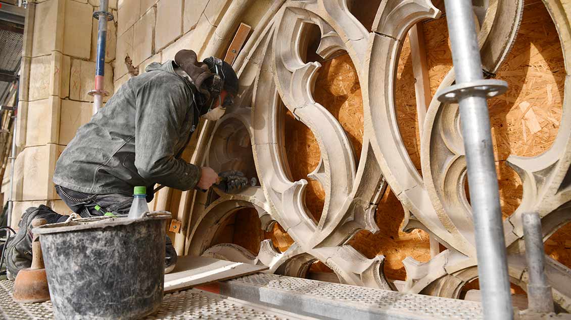 Ein Handwerker schleift ein Relief des Domportals in Münster